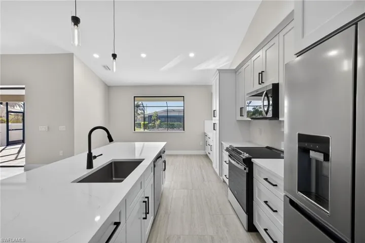 Kitchen with appliances with stainless steel finishes, light stone counters, pendant lighting, white cabinets, and recessed lighting