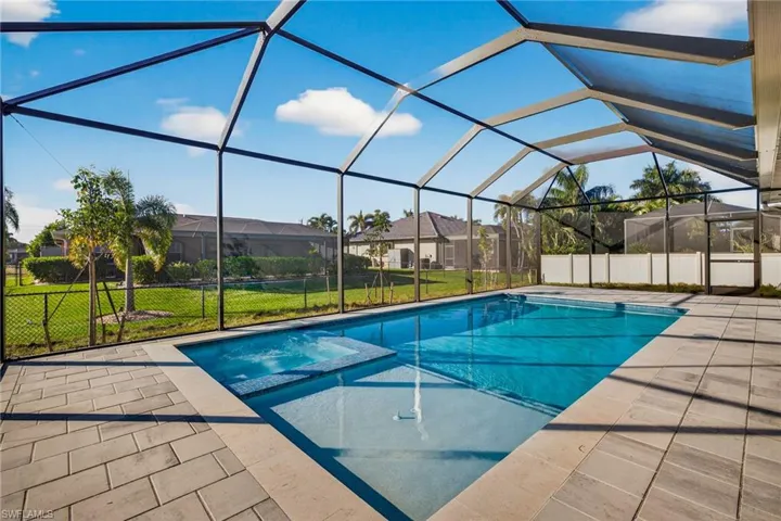 View of pool with a yard, a pool with connected hot tub, a sunroom, glass enclosure, and a patio area