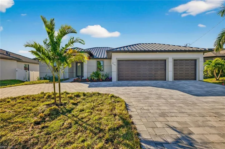 View of front of property featuring a standing seam roof, a metal roof, decorative driveway, stucco siding, and an attached garage