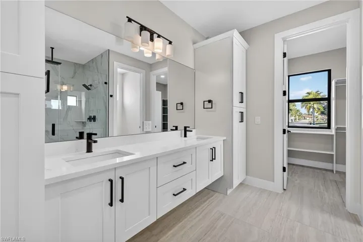 Bathroom featuring a marble finish shower, double vanity, and a spacious closet