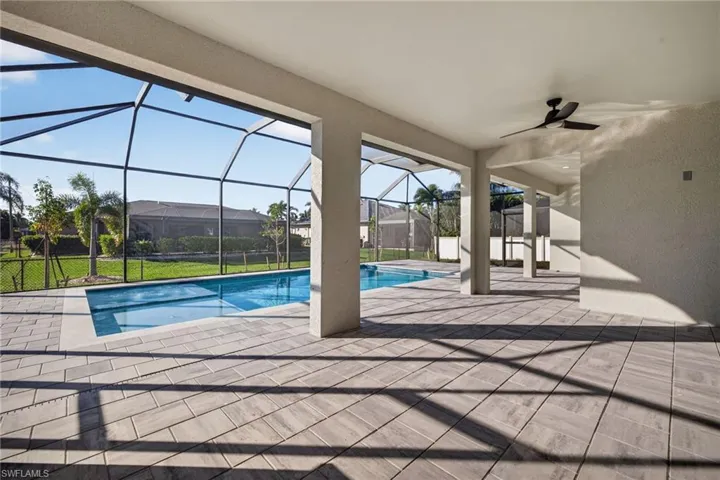 Outdoor pool featuring a patio area, a sunroom, glass enclosure, and a lawn