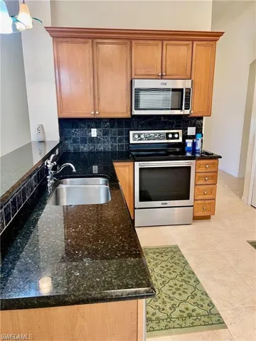Kitchen featuring stainless steel appliances, dark stone countertops, and wood finish cabinets