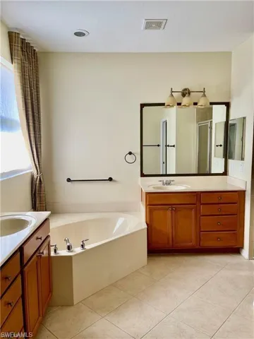 Bathroom with two vanities, a garden tub, a shower stall, and light tile patterned floors