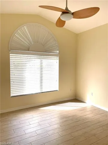 Empty room featuring ceiling fan, light wood-type flooring, and lofted ceiling