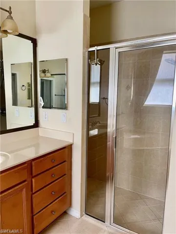 Bathroom with vanity, a stall shower, and light tile patterned flooring