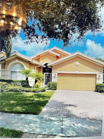 Ranch-style house with stucco siding, a garage, decorative driveway, and a front lawn
