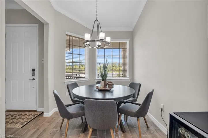 Dining room with an inviting chandelier, baseboards, ornamental molding, and wood finish floors