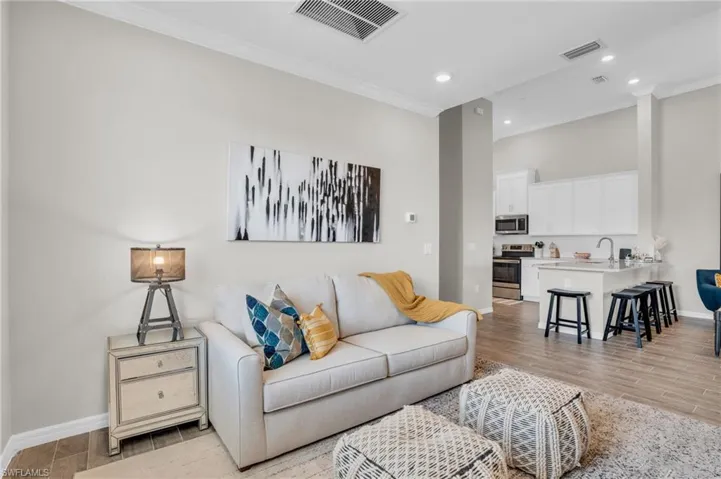 Living room with crown molding, baseboards, visible vents, and light wood-style floors