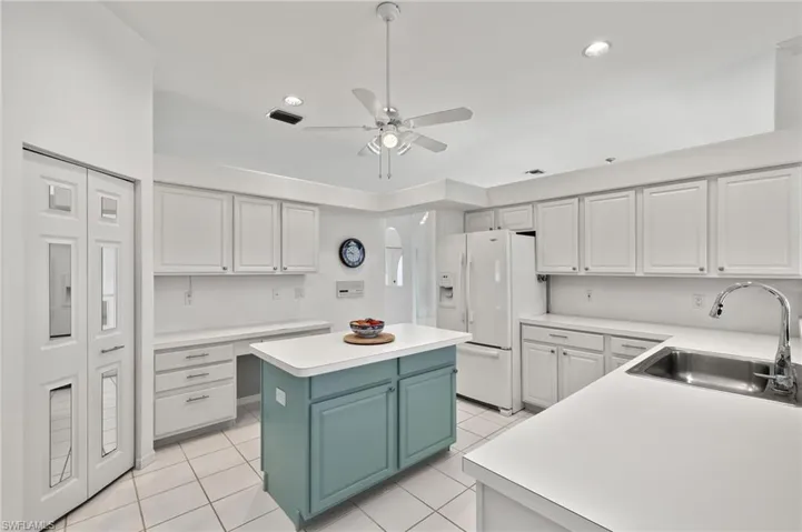 Kitchen featuring a center island, sink, light tile flooring, and ceiling fan