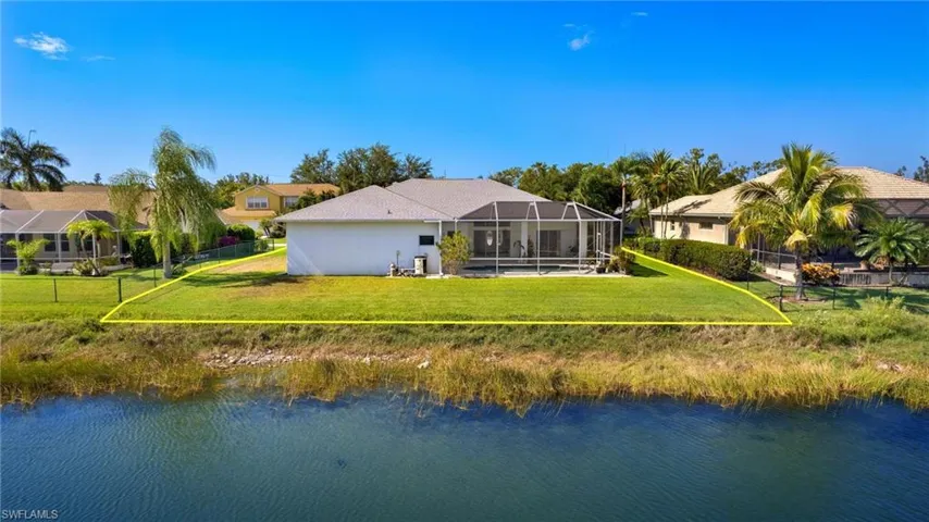 Back of property with a lawn, a lanai, and a water view