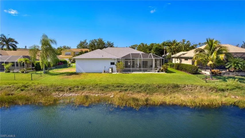 Rear view of property featuring glass enclosure, a water view, and a yard