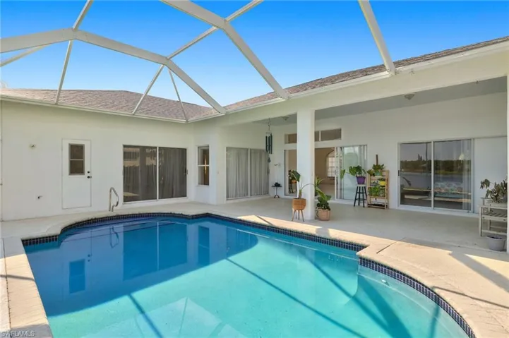 View of pool with a patio area and glass enclosure