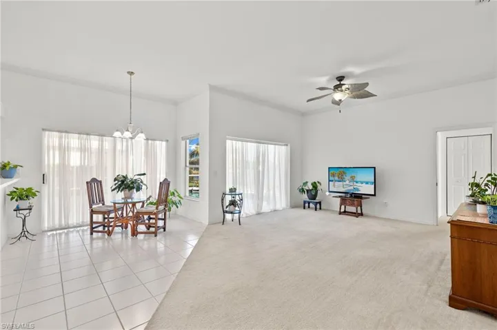 Sitting room featuring ornamental molding, ceiling fan with notable chandelier, and light tile flooring