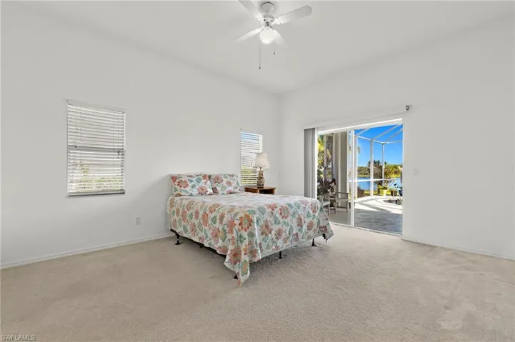Bedroom with ceiling fan, carpet floors, multiple windows, and access to exterior
