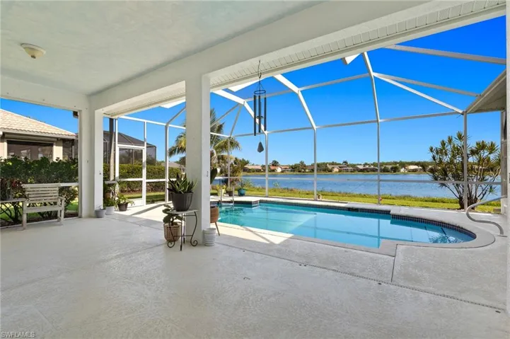 View of pool featuring a water view, glass enclosure, and a patio area