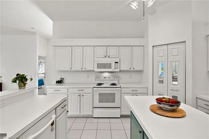 Kitchen featuring ceiling fan, white appliances, white cabinetry, and light tile floors