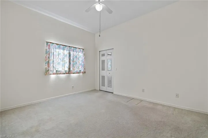 Carpeted empty room with a high ceiling and ceiling fan