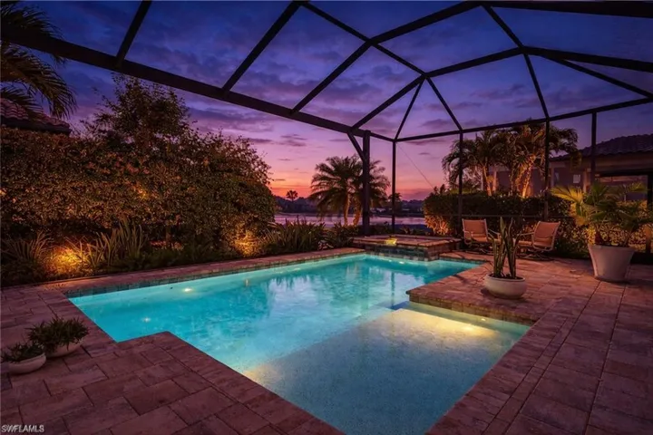 Outdoor pool featuring an in-ground hot tub, glass enclosure, a patio, and a sunroom