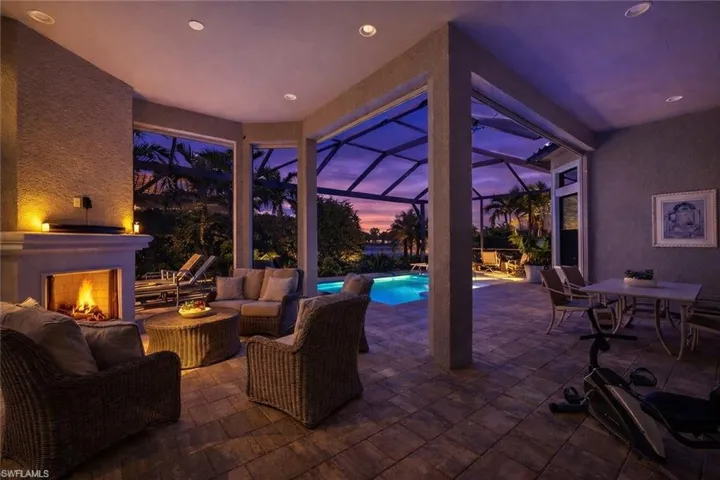 Patio terrace at dusk with a patio area, glass enclosure, a sunroom, an outdoor living / dining area, and an outdoor pool