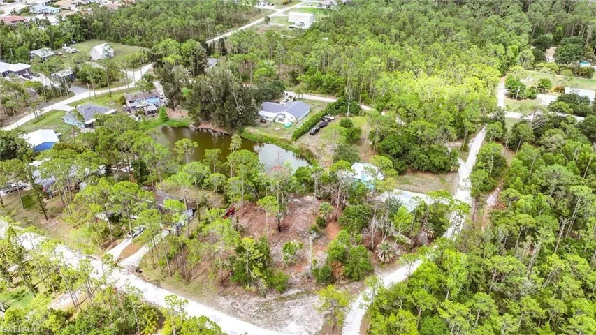 View of property location with a nearby body of water and a forest