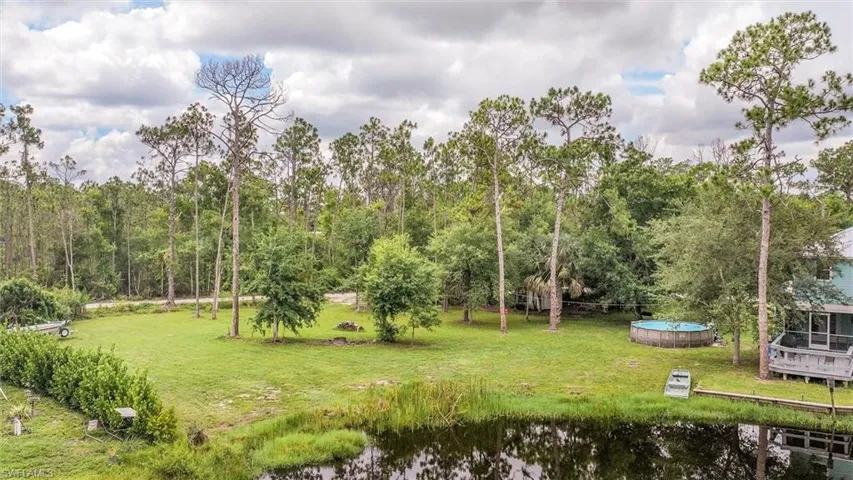 View of grassy yard featuring a water view and an outdoor pool