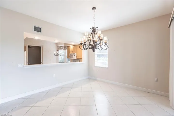 Unfurnished room featuring a chandelier and baseboards