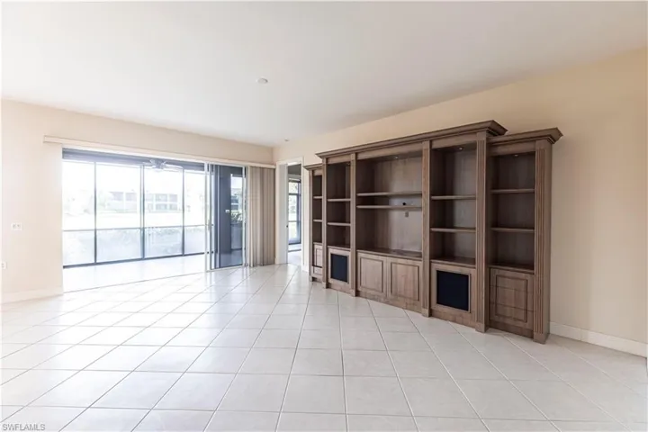 Unfurnished living room with light tile patterned floors and baseboards