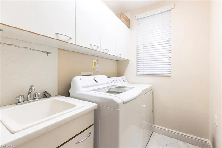Washroom featuring cabinet space, washing machine and dryer, and baseboards