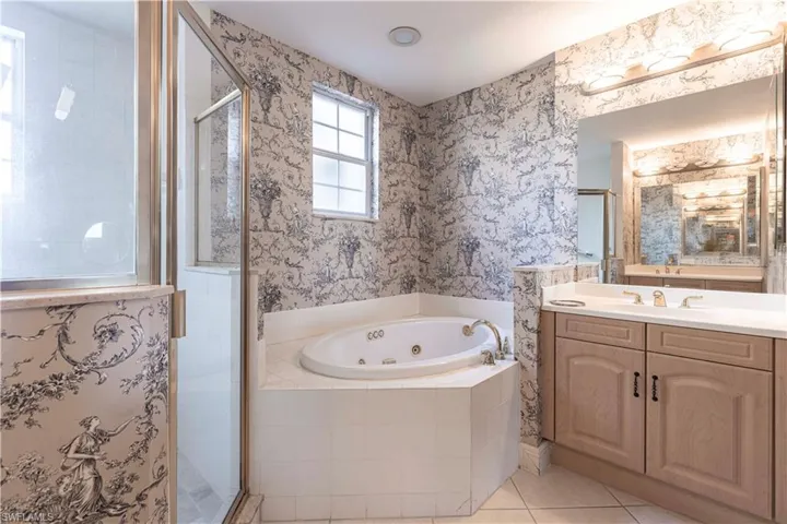 Bathroom featuring a stall shower, vanity, a jetted tub, tile patterned floors, and wallpapered walls