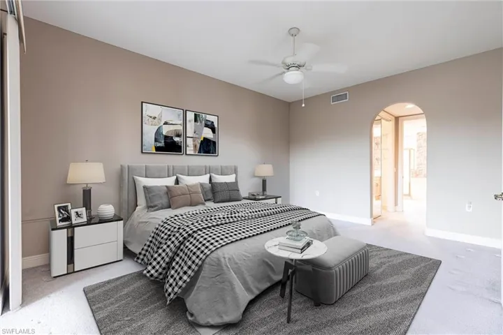 Bedroom with arched walkways, light carpet, and ceiling fan