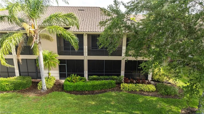 Rear view of property featuring a tiled roof, a yard, and stucco siding