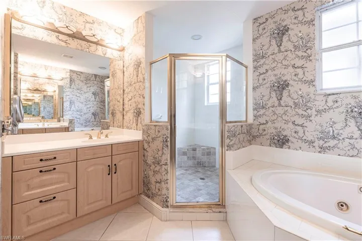 Bathroom featuring a stall shower, a tub with jets, vanity, healthy amount of natural light, and wallpapered walls