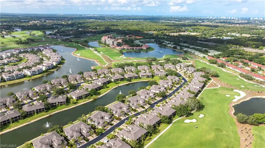 Aerial view of property and surrounding area featuring nearby suburban area, a large body of water, and a golf course