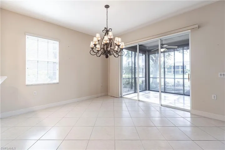 Unfurnished room with light tile patterned floors, baseboards, and a chandelier