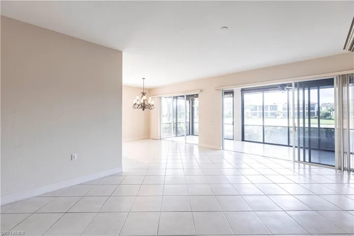 Empty room with a chandelier, baseboards, and light tile patterned floors