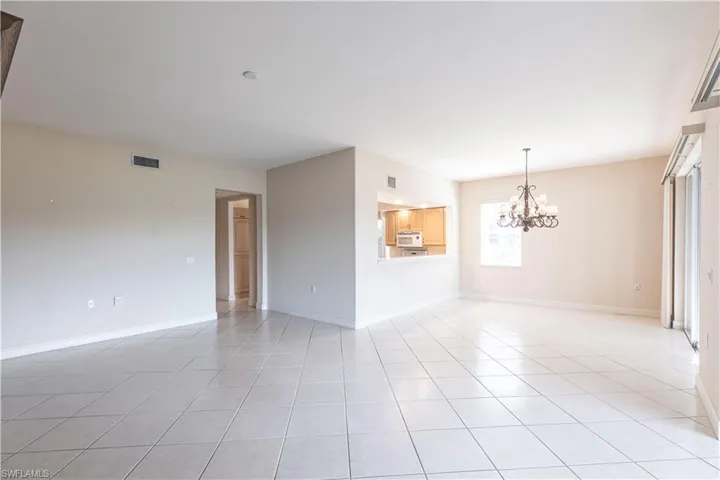 Unfurnished room featuring a chandelier, light tile patterned floors, and baseboards