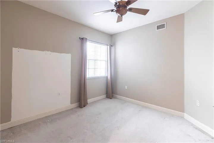 Empty room featuring ceiling fan, light carpet, and baseboards