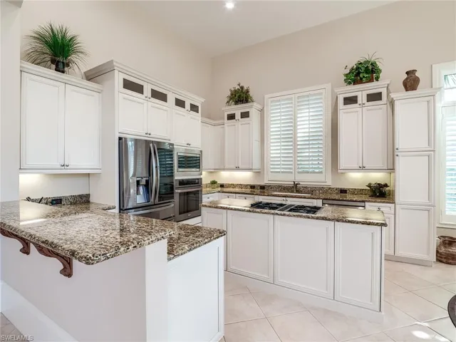 Kitchen with stainless steel appliances, white cabinets, a wealth of natural light, and light tile floors