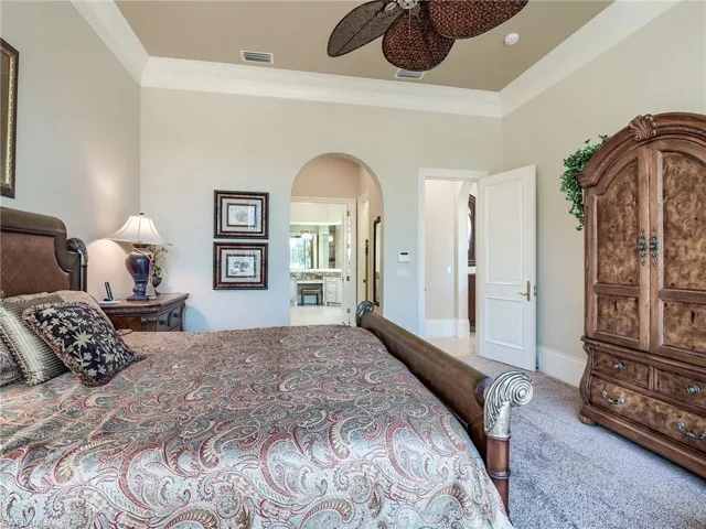 Bedroom featuring ornamental molding, carpet, ceiling fan, and ensuite bath