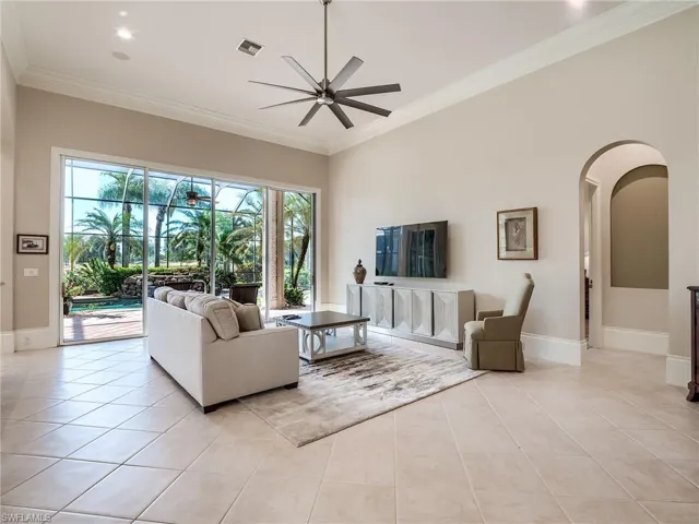 Tiled living room featuring crown molding, a towering ceiling, and ceiling fan