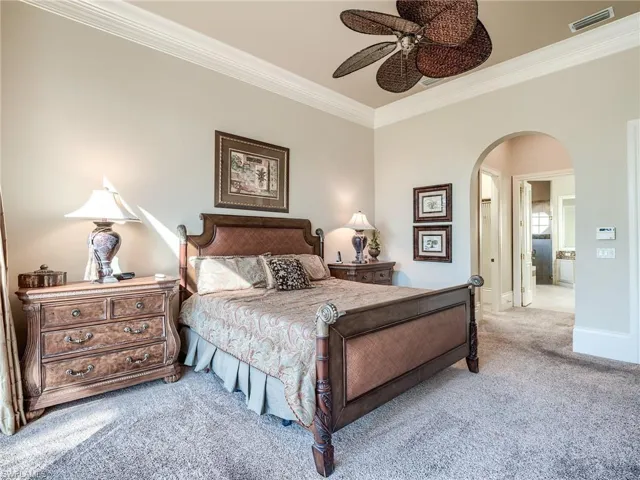 Carpeted bedroom featuring ceiling fan, crown molding, and connected bathroom
