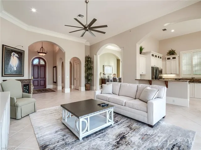 Living room with ornamental molding, ceiling fan, and light tile floors