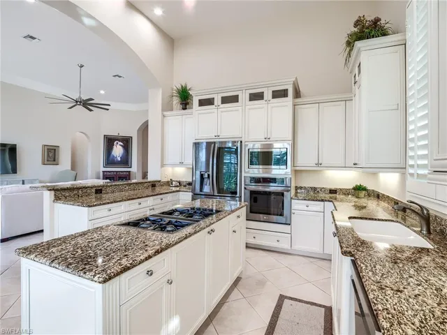 Kitchen with a center island, crown molding, appliances with stainless steel finishes, sink, and light tile floors