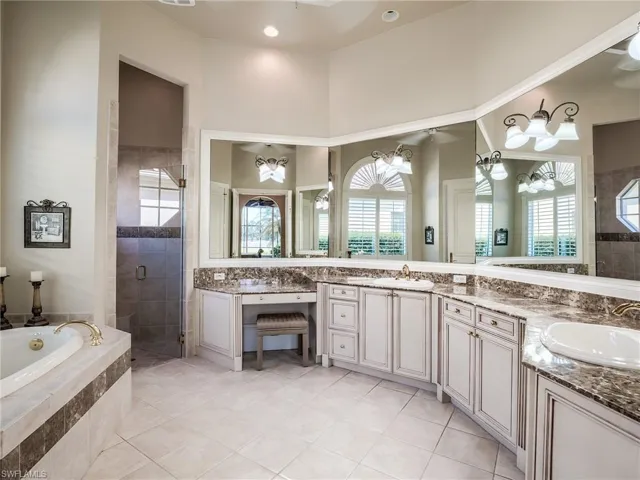 Bathroom featuring dual vanity, ceiling fan with notable chandelier, tile floors, and plus walk in shower