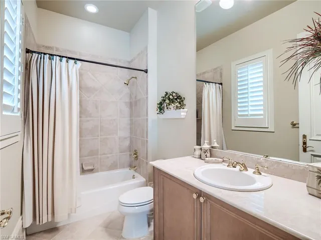 Full bathroom with tile flooring, shower / bath combination with curtain, vanity, and toilet