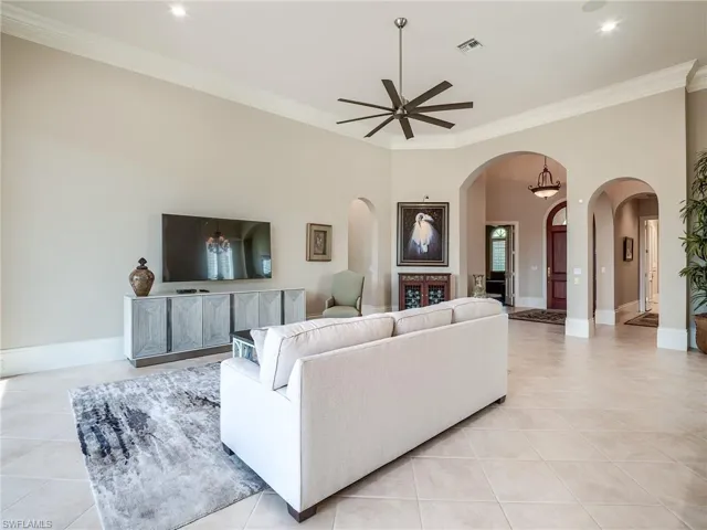 Tiled living room with ceiling fan, ornamental molding, a fireplace, and a towering ceiling