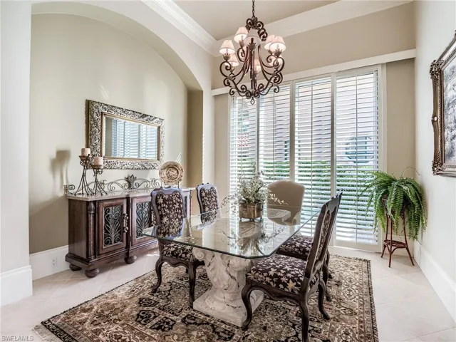 Tiled dining room featuring a healthy amount of sunlight, crown molding, and a chandelier