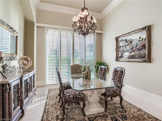 Dining room featuring tile floors, a wealth of natural light, ornamental molding, and an inviting chandelier