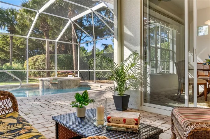 View of swimming pool featuring a patio area, glass enclosure, a sunroom, and a pool with connected hot tub