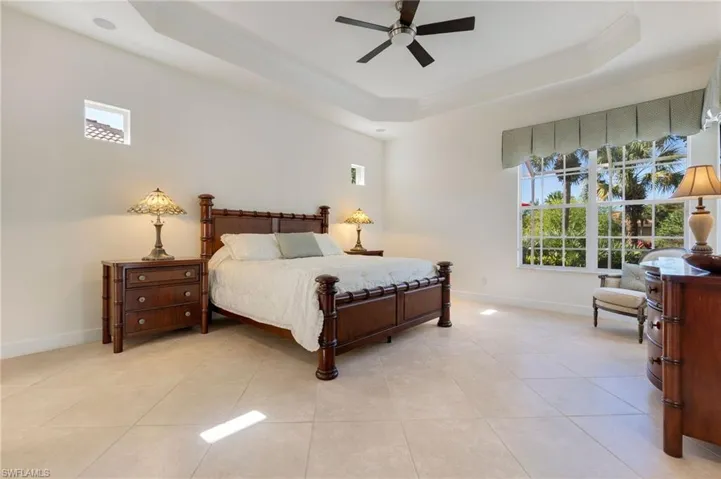 Bedroom with a raised ceiling, a ceiling fan, crown molding, and light tile patterned floors